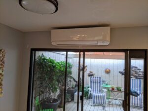 White wall mounted mini split air conditioner mounted above a glass sliding door.
