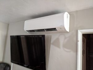 White wall-mounted indoor unit mounted above a large TV set