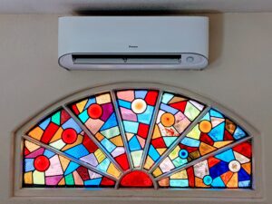 White wall-mounted Daikin Mini Split Air Conditioner inside unit installed by Accord Air in San Diego above a stained-glass window.