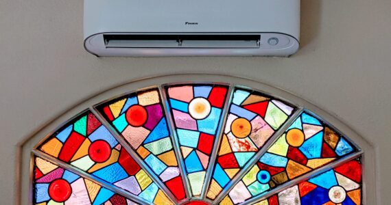 White wall-mounted Daikin Mini Split Air Conditioner inside unit installed by Accord Air in San Diego above a stained-glass window.
