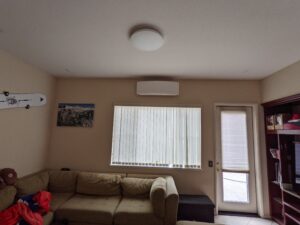Mini Split Air Conditioner inside unit installed by Accord Air in the living room with couch, wardrobe, door, window, picture.