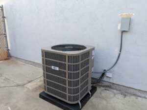 AC PRO heat pump installed next to the white wall outside the building.
