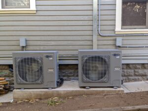 Two AC PRO air conditioners are installed against the wall of the mobile home.