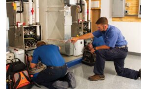 Two technicians installing a gas furnace.
